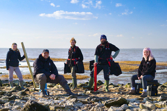 5 members of staff standing on beach with seagrass equipment
