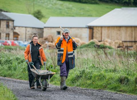 Stirley Farm volunteers, in high-vis with a wheelbarrow