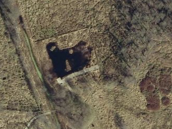 An aerial photo of Askham Bog in 2005. The land is largely open with little tree cover, and the dark spot in the centre is the pond.