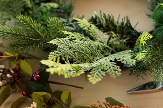 Image showing some evergreens and a variety of flowers and leaves ready to decorate a wreath on a table.