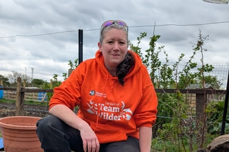 volunteer crouched down over a garden pond