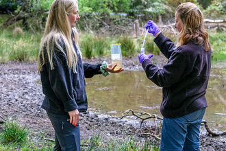 two women stood next to a pond carrying out newt surveillance