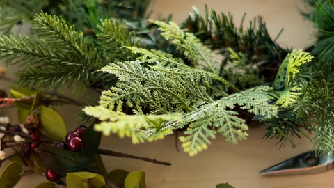 Image showing some evergreens and a variety of flowers and leaves ready to decorate a wreath on a table.