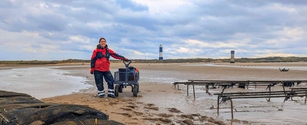 Woman standing at the oyster trestles on the sandy seashorecredit Simon Welton
