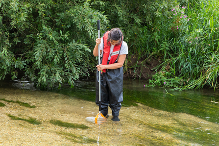 Volunteer in kick sampling kit, standing in the stream