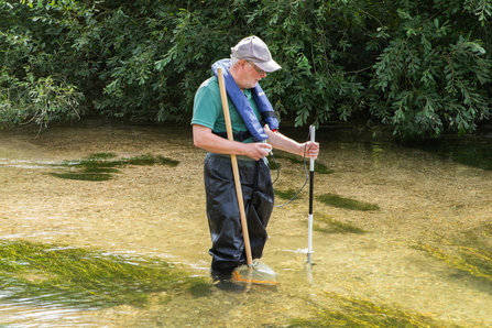 Volunteer standing in the stream using a waterflow meter