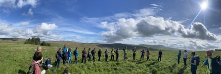 group of people stood in a circle in a field on a sunny autumn day