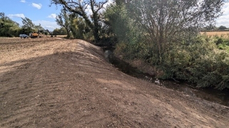 A large soily bank slopes gently down to the foss (right)