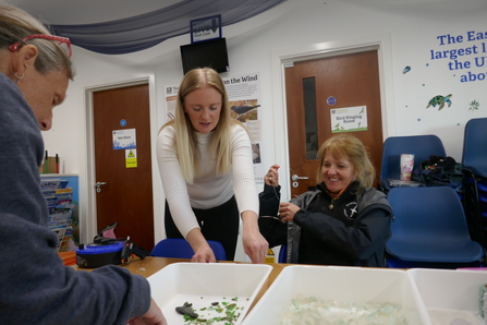 Volunteer being shown how to make jewellery out of seaglass