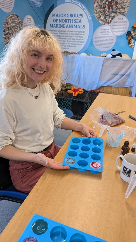 Smiling female staff member making soap in moulds