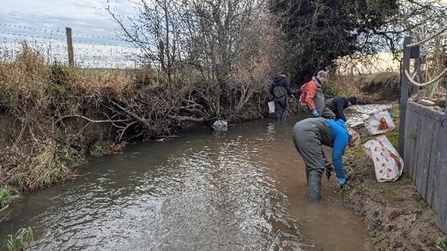 Staff are bent over at the right hand side of the river.