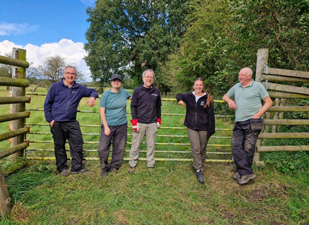 Volunteers on site leaning against a fence