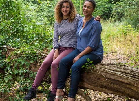 Juliet and Amy sit together on a fallen tree