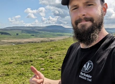 Man stood in field smiling with thumbs up